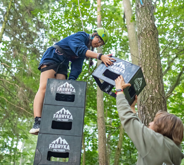 dziewczyna buduje wieżę ze skrzynek na wycieczce szkolnej