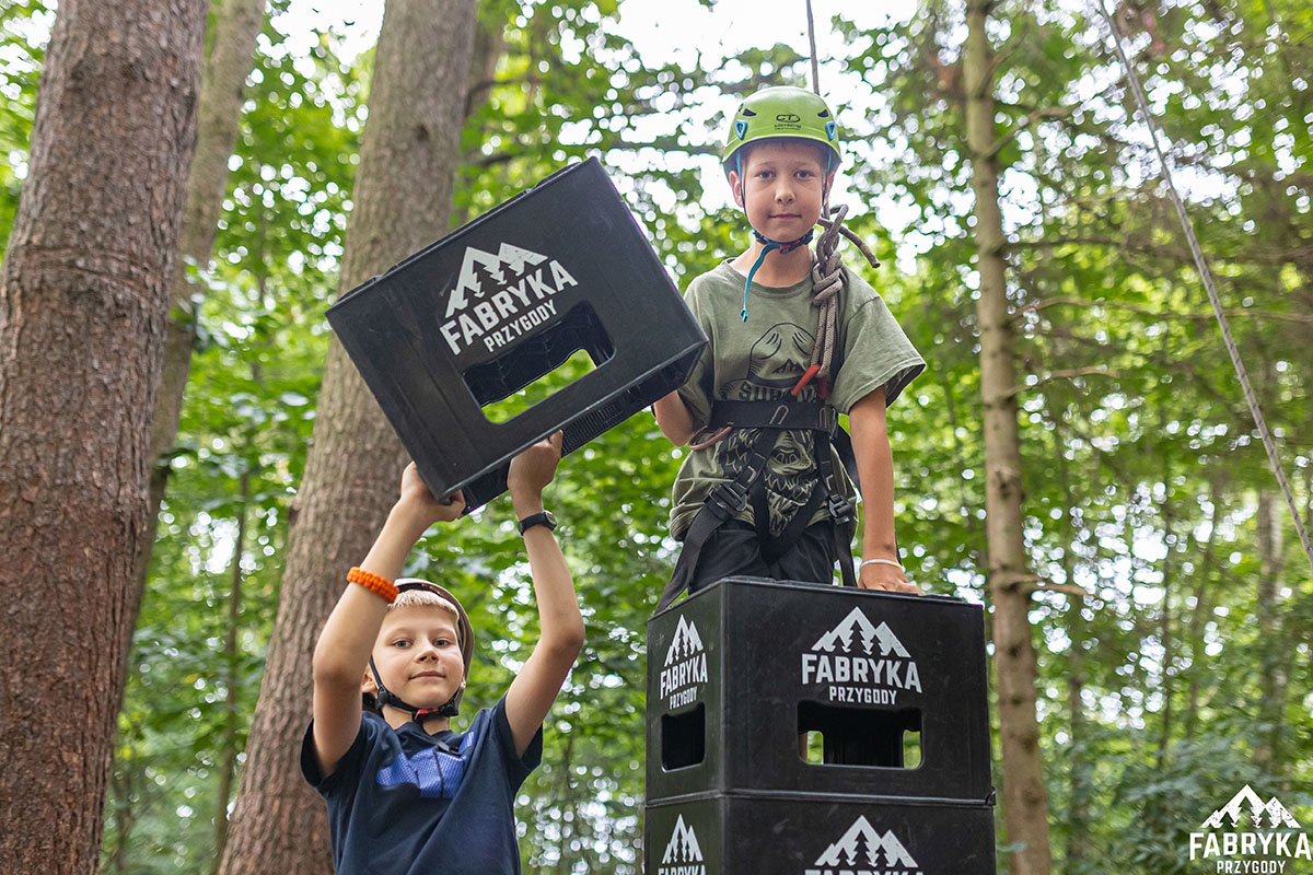 szczęśliwe dzieci na wyciczece szkolnej budują wieżę ze skrzynek