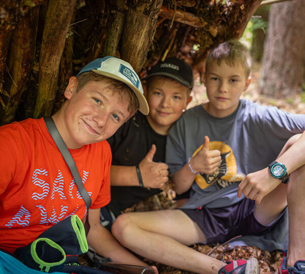 grupa chłopców na wycieczce szkolnej w szałasie